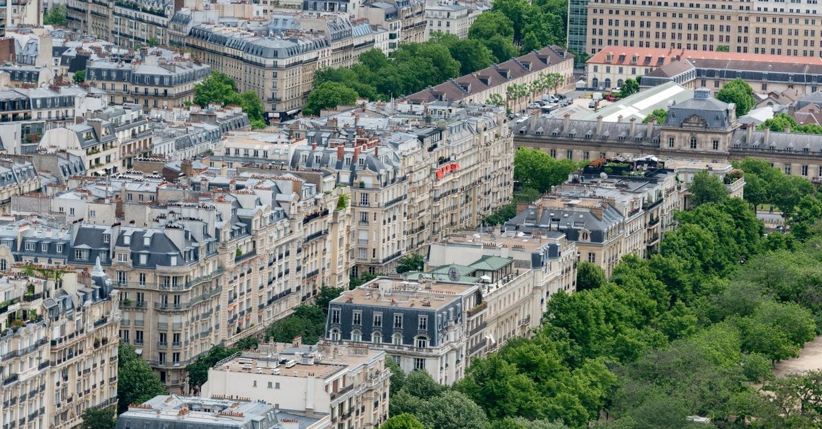 Stunning aerial view of classic Parisian architecture surrounded by greenery during summer.