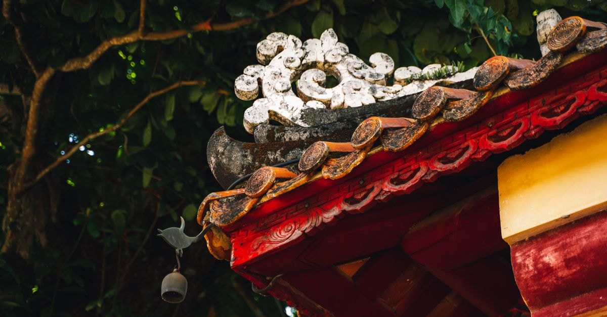 Huế Travel Guide: Planning Tips, Costs and Things to Do Intricate roof detail of a traditional temple in Huế, showcasing vibrant colors and Asian architectural elements.