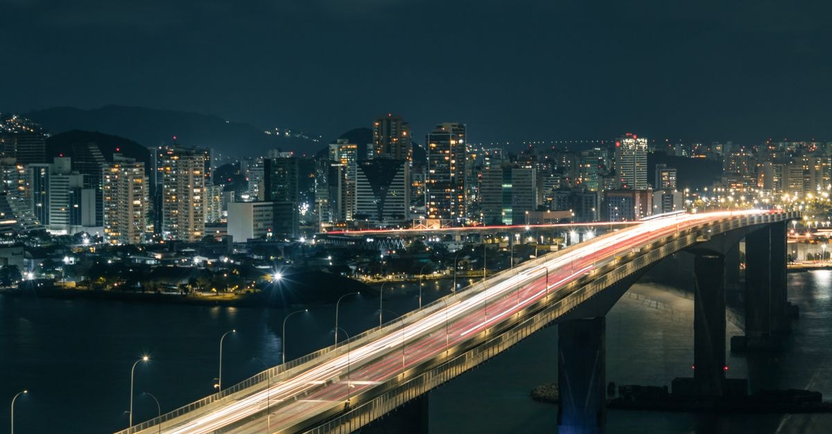 Montaña Suites Hotel in Petare: Tropical Details by the Poolside Terrace Aerial view of a lit-up city bridge showing light trails against a vibrant urban skyline at night.