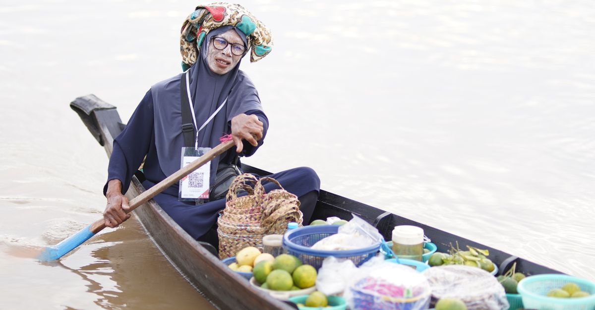 Holiday Inn Express & Suites Banjarmasin: Effortless Comfort in South Kalimantan Elderly woman selling goods on a boat at Banjarmasin's floating market, South Kalimantan, Indonesia.