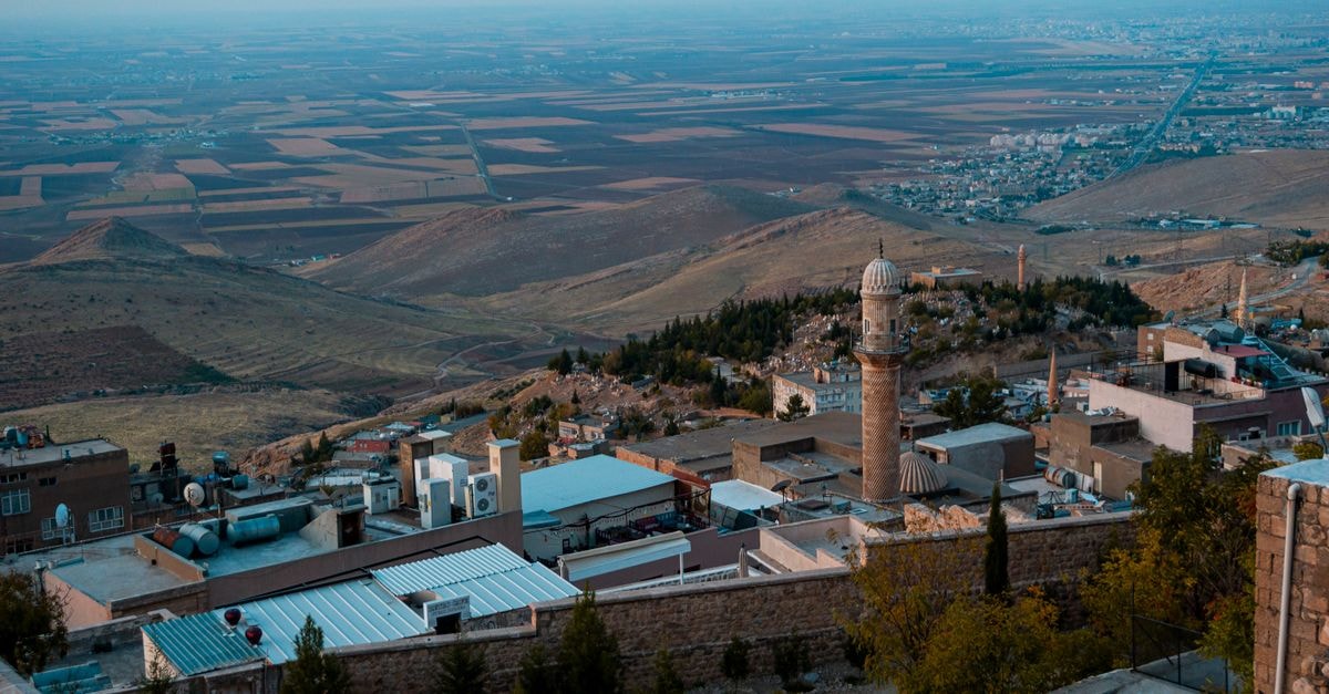 High-angle view of Mardin's rooftops and ancient minaret against a sprawling landscape.