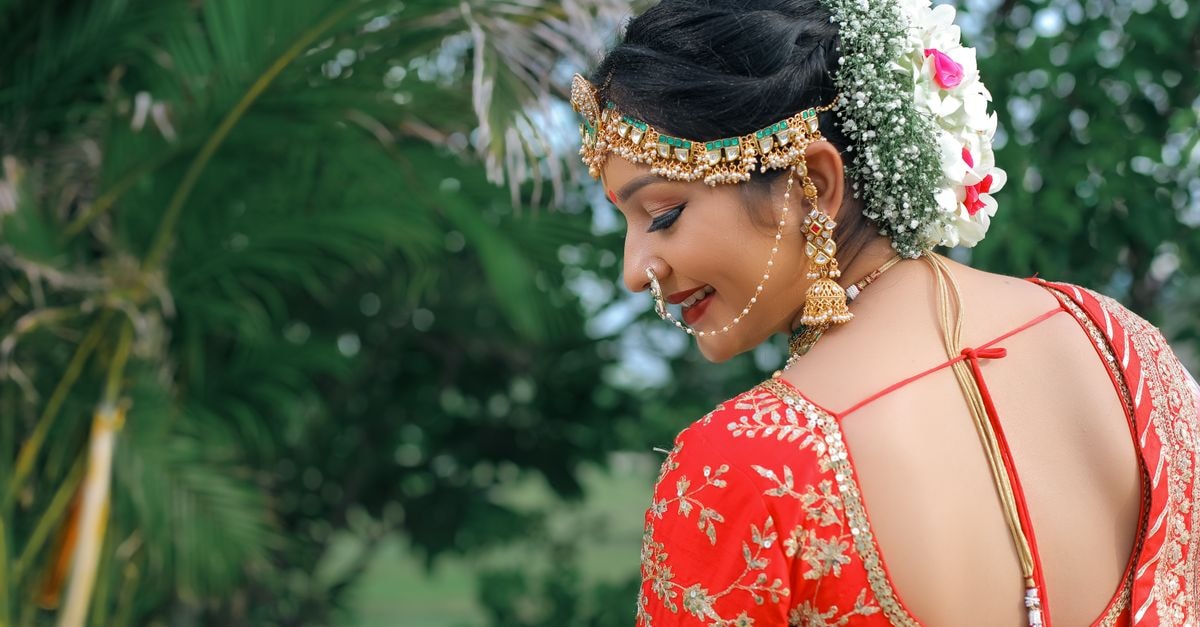 Hotel Classique in Rajkot: Raiya Road Address, Event Space and Listed Amenities A beautiful Indian woman in traditional attire stands outdoors, adorned with jewelry and flowers in her hair.