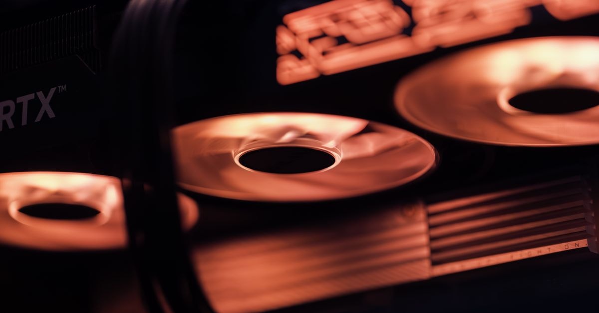 Pre-built gaming PCs edge into the mainstream as 2026 retailer deals cut prices on RTX 5070 Ti systems Dynamic close-up shot of illuminated gaming graphics card fans in red light, showcasing cutting-edge technology.