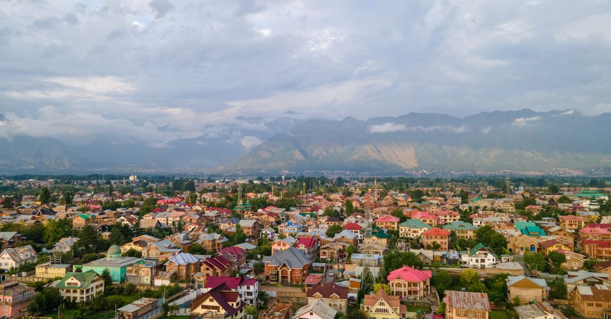 Darussalam Restaurant & Inn in Srinagar: A Stay on Qamarwari-Batamalo Road Stunning aerial view of colorful Srinagar city with Himalayan backdrop under cloudy skies.