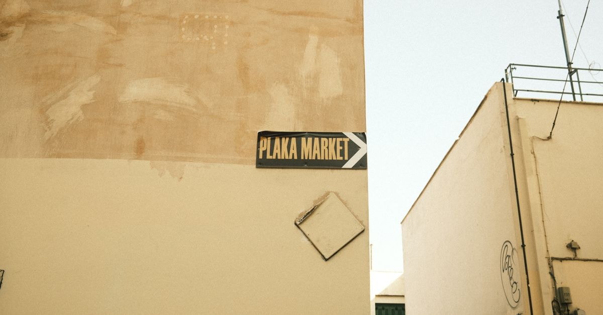 Directional sign to Plaka Market on a rustic urban wall, capturing a vintage city vibe.
