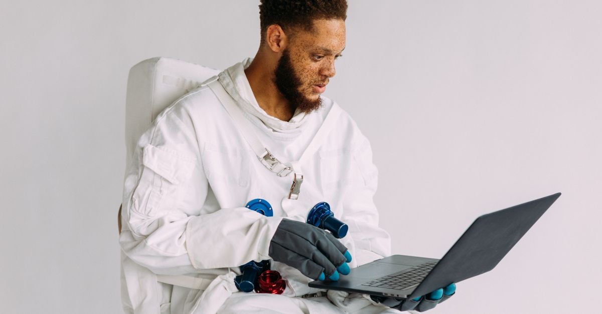 NASA Releases Lunar Orbiter Images of Crater Left by Crashing SpaceX Rocket An astronaut in a space suit operating a laptop indoors, conveying technological themes.