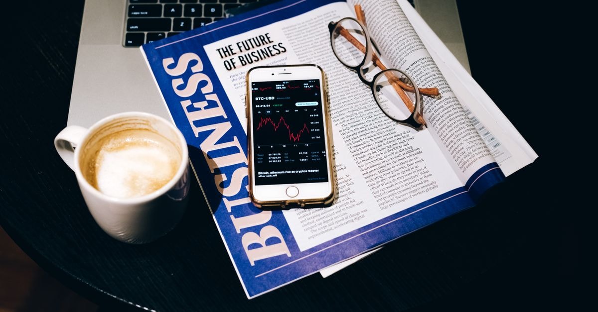Palantir trades near record highs as analysts split on valuation after Q2 results A business setup with a laptop, coffee, phone, and newspaper. Perfect for finance themes.