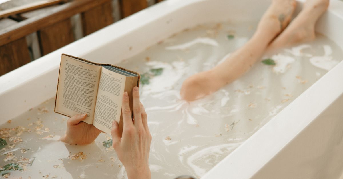 Cozy indoor scene of a person reading in a bathtub surrounded by warm light.