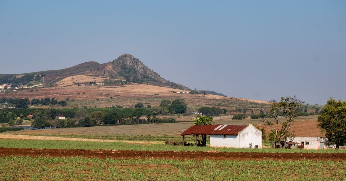 Manzini Travel Guide: Markets, Braais, and Mountain Day Trips Beautiful rural landscape in Manzini, Eswatini featuring fields, a rustic building, and mountain views.