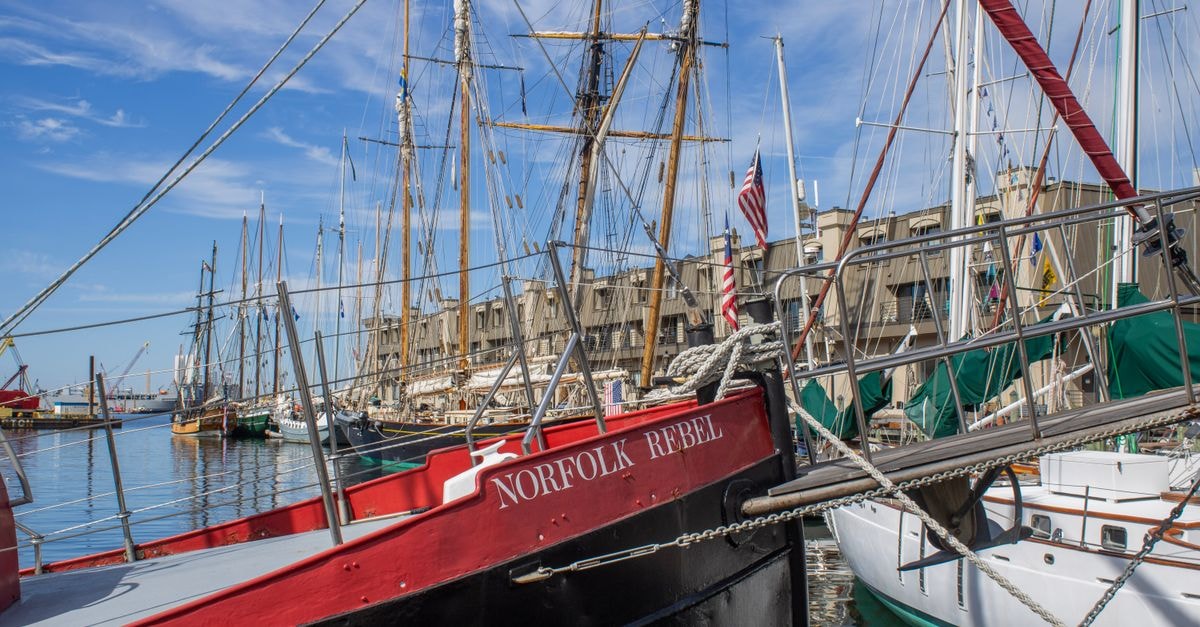 Baltimore travel guide: exploring the Chesapeake's cultural capital Scenic view of historic sailboats moored in Norfolk, Virginia harbor under a blue sky.