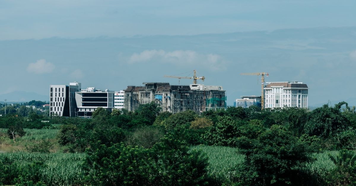 Cityscape of Kon Tum, Vietnam showing urban development amidst greenery with construction cranes.