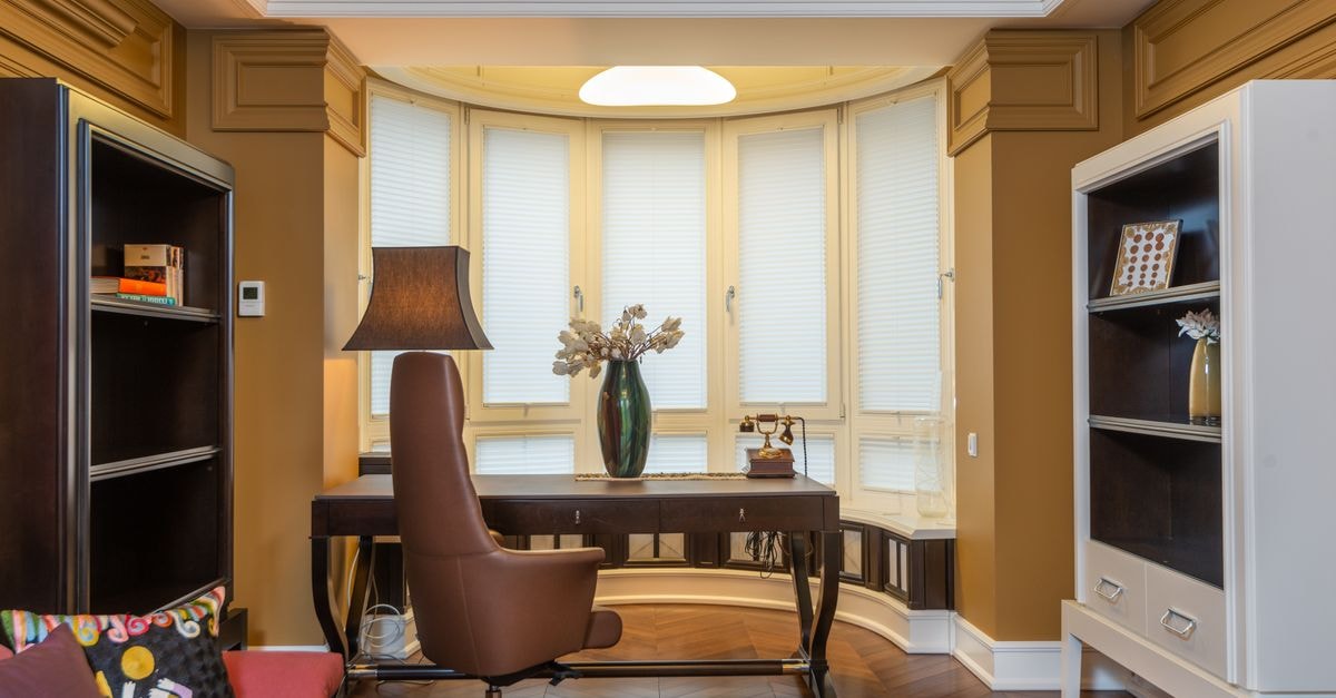 Stylish home office featuring a comfortable armchair, desk, bookshelves, and decorative elements.