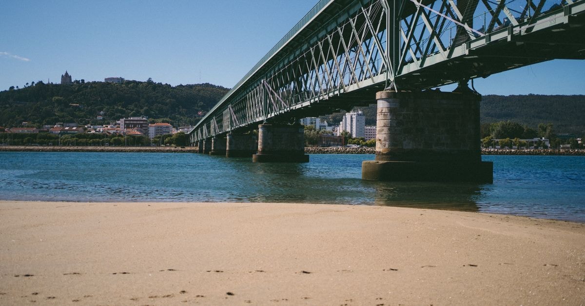 Viana do Castelo Travel Guide: Planning Tips, Costs and Things to Do A clear summer day view of the Eiffel Bridge over the Lima River in Viana do Castelo, Portugal.