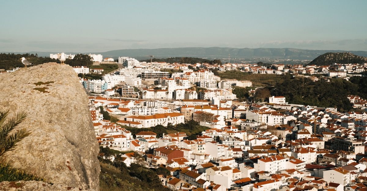 Scenic aerial view of a European town with white and red-roofed buildings under a clear sky.