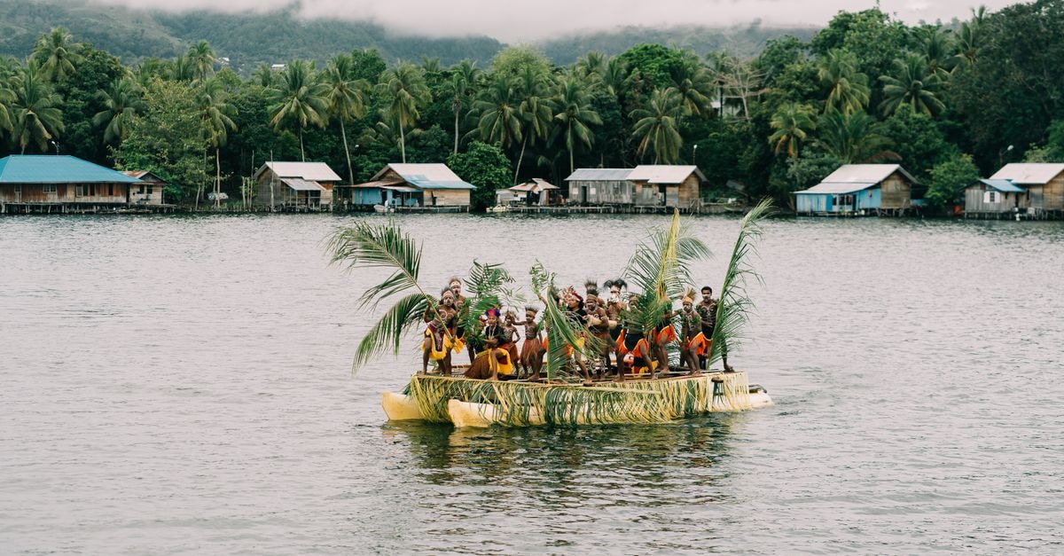 Swiss-Belhotel Jayapura, Papua — Jotefa Bay Views from the Business District A group of people aboard a traditional boat on a serene lake in Papua, Indonesia.