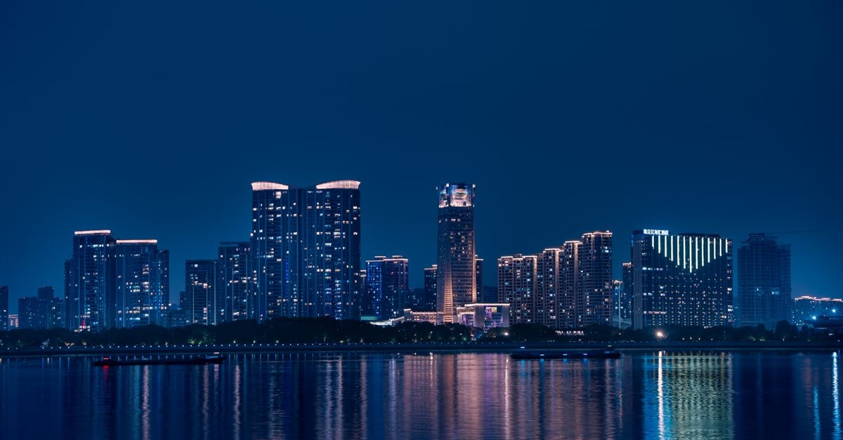 Jinghu Hotel in Yangjiang: A Lakeside Retreat Since 2003 Stunning night view of Hangzhou's skyline reflecting on Qiantang River, showcasing modern architecture.