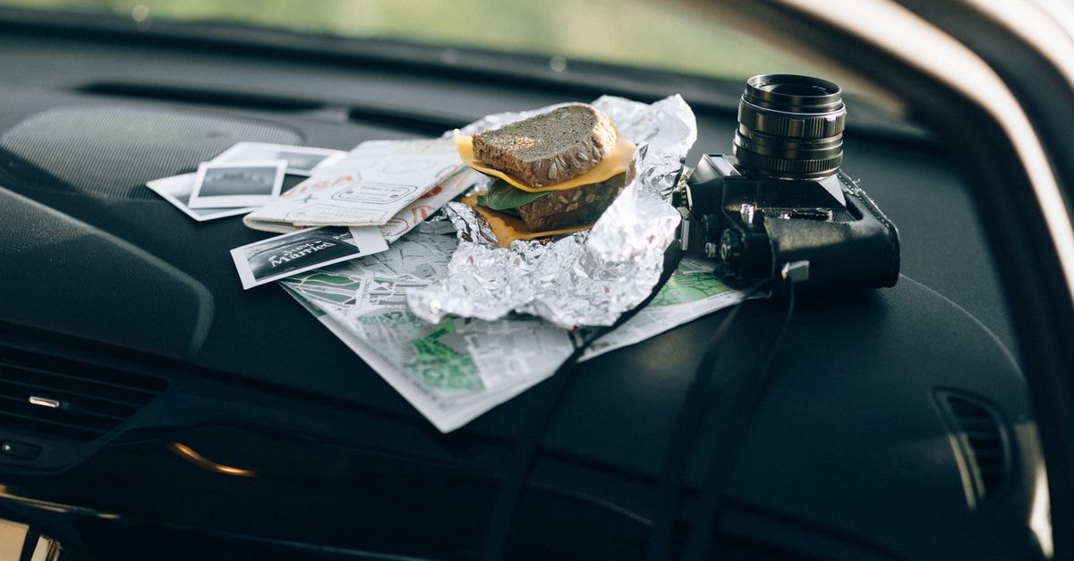 Celaya Travel Guide: Planning Tips, Costs and Things to Do A camera and a sandwich wrapped in foil placed on a car dashboard with maps and photos.