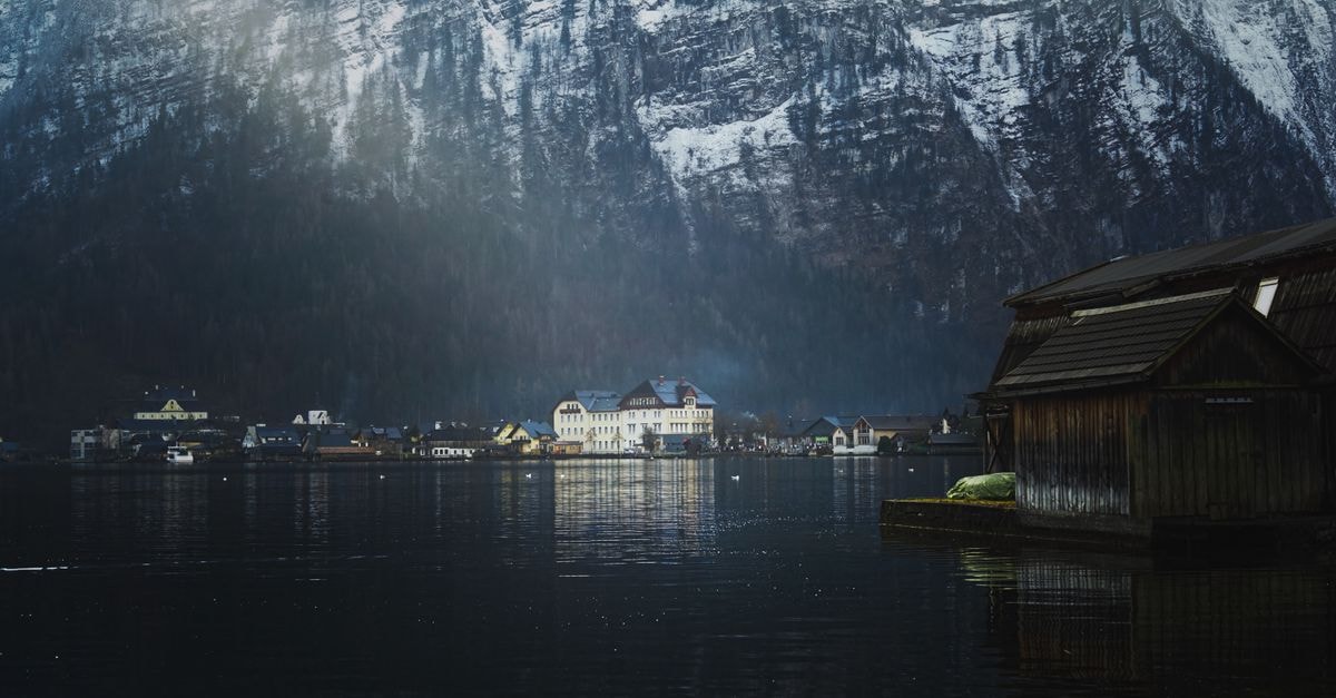 Heritage.Hotel Hallstatt in Hallstatt: Three Historic Townhouses by the Lake Picturesque view of Hallstatt, Austria with snowy mountains reflecting in the lake at twilight.