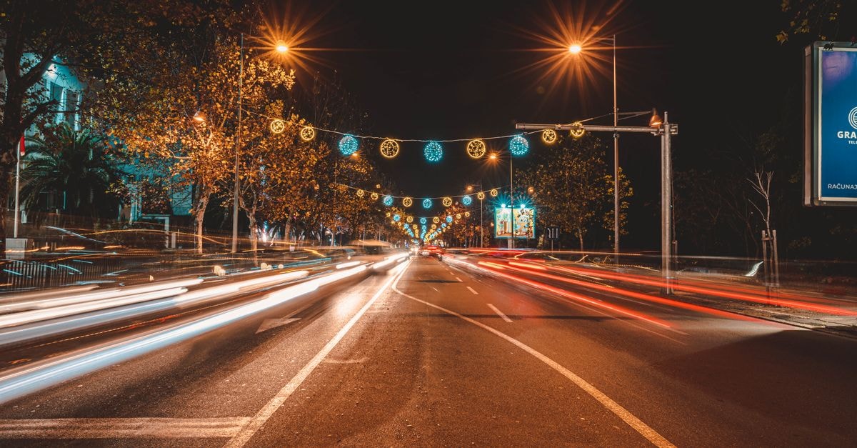 Vibrant city street in Podgorica, Montenegro with festive lights and long exposure traffic trails at night.