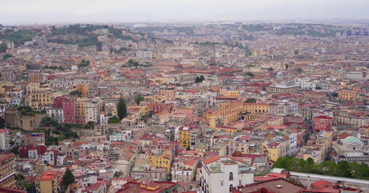 Naples travel guide: getting around, eating well, and planning smart Panoramic view of Naples showcasing historic architecture and densely packed rooftops under an overcast sky.