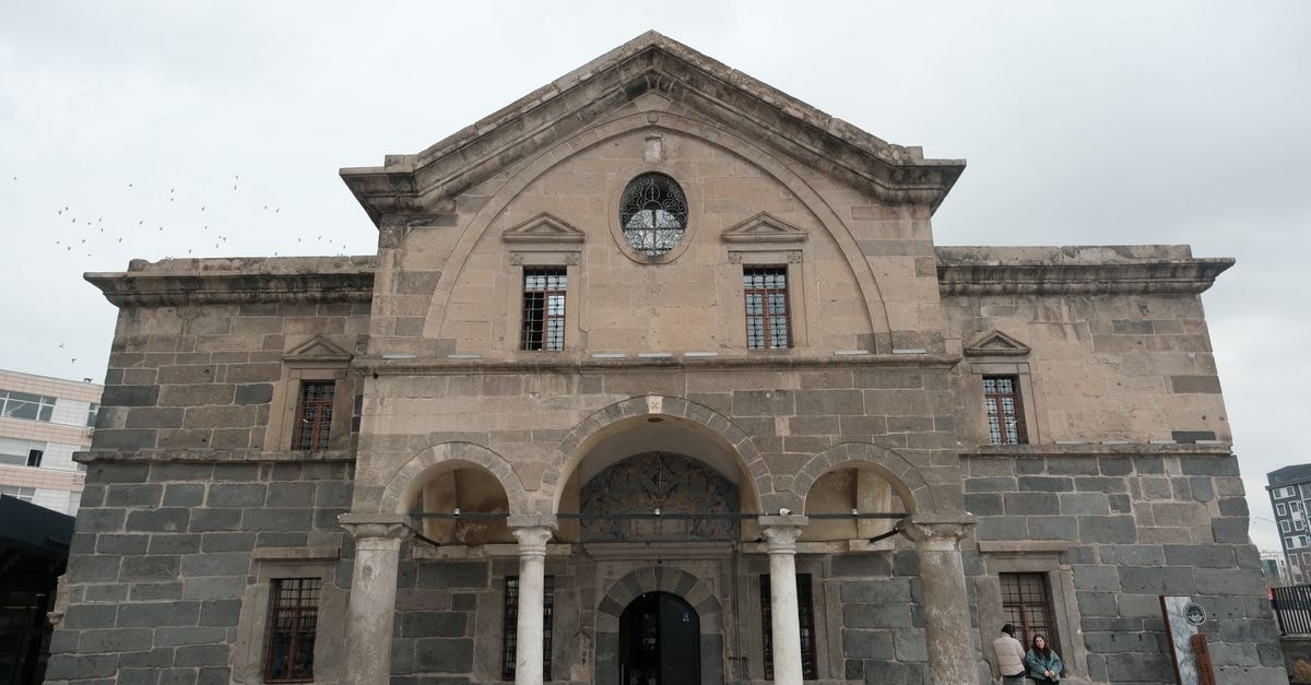 Diyarbakır travel guide: basalt walls, layered history, and slow southeastern rhythms Front view of an ancient stone building with archways and classic architecture under a cloudy sky.