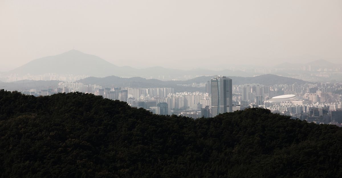 Hotel Gracery Seoul: A Third Space Near Namdaemun and Myeongdong Aerial skyline of Seoul from forested hillsides, featuring distant mountains.