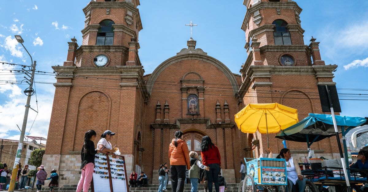 Ambato Travel Guide: Planning Tips, Costs and Things to Do Bustling street market scene with vendors and visitors outside a historic church in Peru.