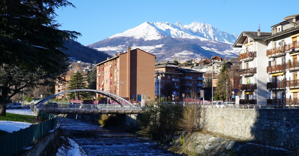 Andorra la Vella Travel Guide: A Compact Pyrenean Capital Picturesque view of a mountain town with buildings, a river, and a bridge under a clear blue sky.