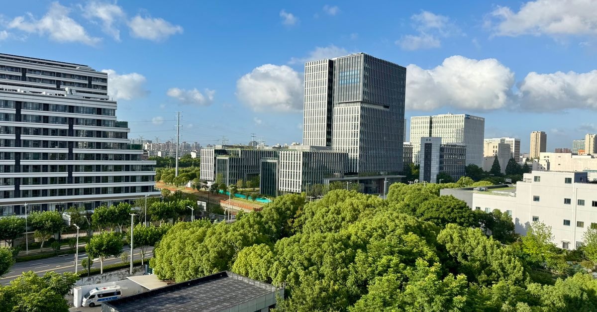 Vienna Hotels, Zhongshan — A 2019-Renovated Stay on Kanghua Road Aerial view of modern buildings and lush greenery in Shanghai, China under a bright, clear sky.