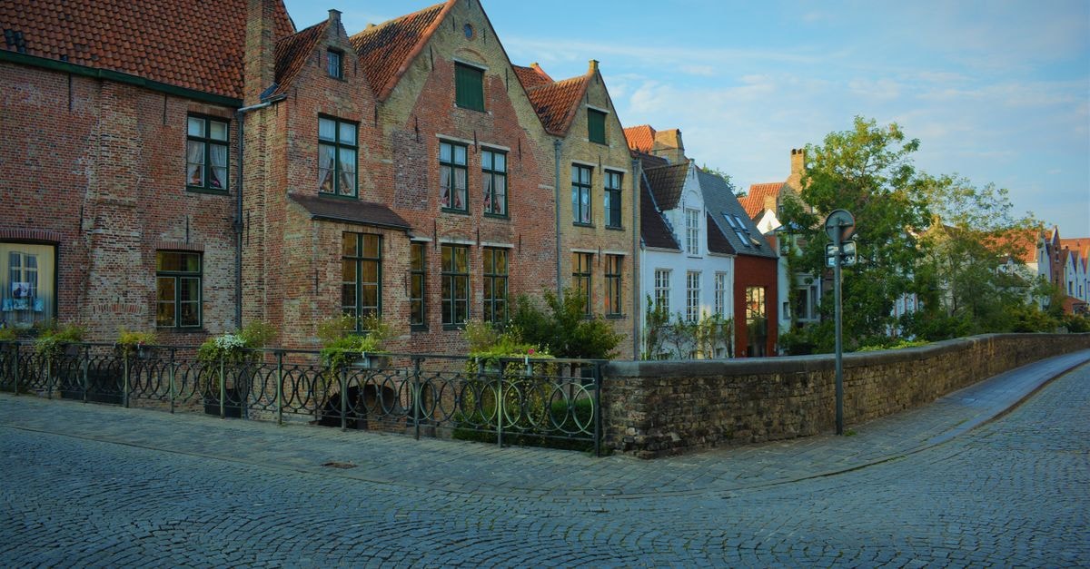 Bourgoensch Hof in Bruges: A canal-side stay near Markt Picturesque view of medieval houses lining a cobblestone street in Bruges, Belgium.