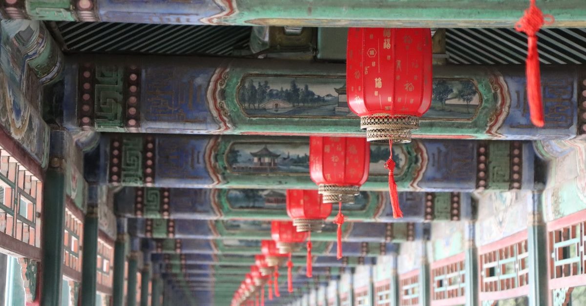 Chengguan Qu Travel Guide: Palaces, Art, and Dining Close-up of traditional red lanterns hanging in Beijing's Summer Palace with intricate ceiling artwork.