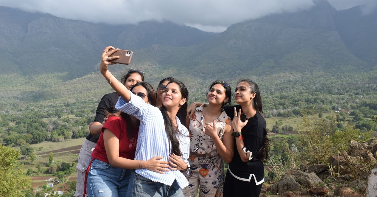 Coimbatore Travel Guide: Gateway to the Western Ghats A group of young women taking a selfie together with scenic hills in the background at Masinagudi, Tamil Nadu.