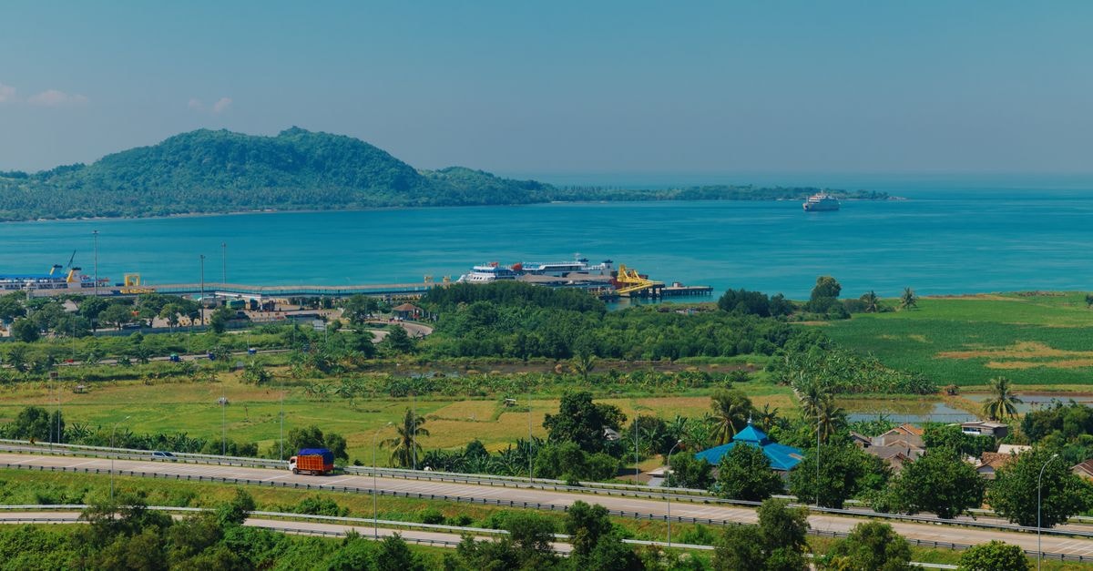 Bandar Lampung Travel Guide: Coastal Gateway of Sumatra A beautiful view of Indonesia's coast, lush greenery, and distant mountains over a clear ocean.