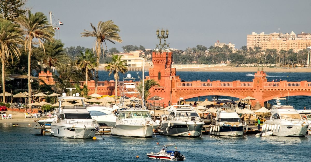 Red Confort Hotel, Alexandria — A Boutique Stay Near the Cathedral A scenic view of yachts docked by a historic bridge in Alexandria, Egypt.