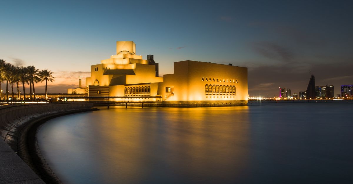 Doha Travel Guide: City Contrasts and Culture Captivating night scene of the Museum of Islamic Art in Doha, Qatar, reflecting beautifully over calm waters.