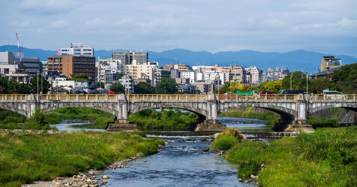 Dormy Inn Maebashi in Gunma: Hot Springs Near JR Maebashi City bridge spanning a serene river with mountain backdrop, showcasing urban tranquility.