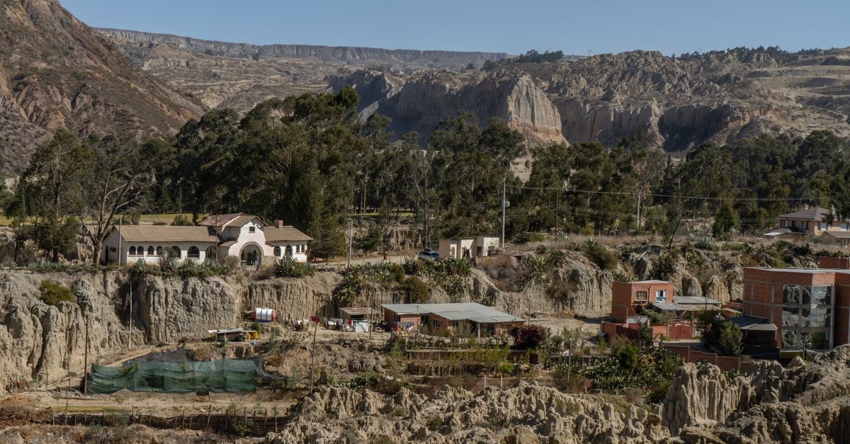 Tarija Travel Guide: A Slow Look at Bolivia's Wine Country Capital Sunlit La Paz village with dramatic eroded rock formations and lush trees.
