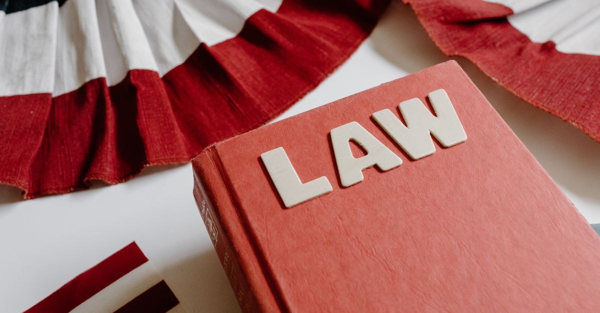 A law book with bold letters placed beside a red, white, and black decorative ribbon.