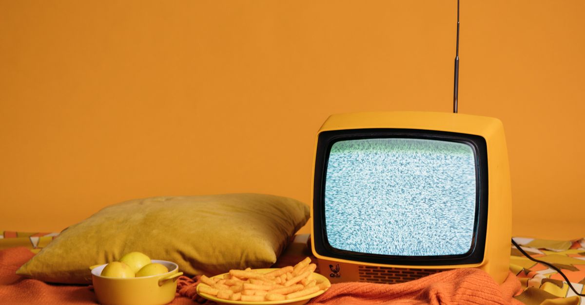 Apple TV Confirms 2026 Slate Changes as 'Rings of Power' Unveils Season 3 Trailer and Casts Simon Pegg A vintage yellow TV with static, surrounded by fries, apples, and a cozy pillow setup.