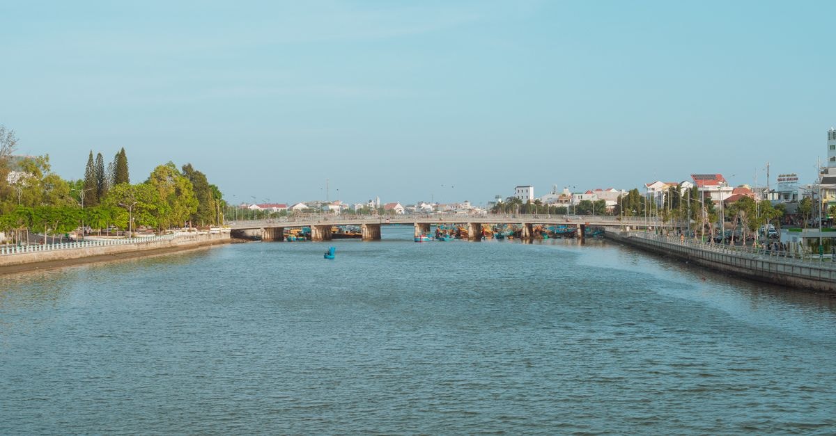 Beautiful river landscape with a bridge in Bình Thuận, Vietnam, under a clear blue sky.