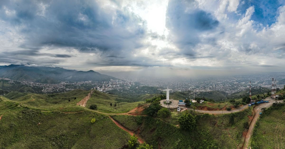 Palmira travel guide: sugarcane country and Valle del Cauca charm Stunning aerial panorama of Cali, Colombia featuring Cristo Rey statue under dramatic skies.