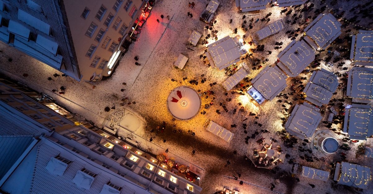 Aerial perspective of Tallinn's festive Christmas market at night with glowing lights and snow.