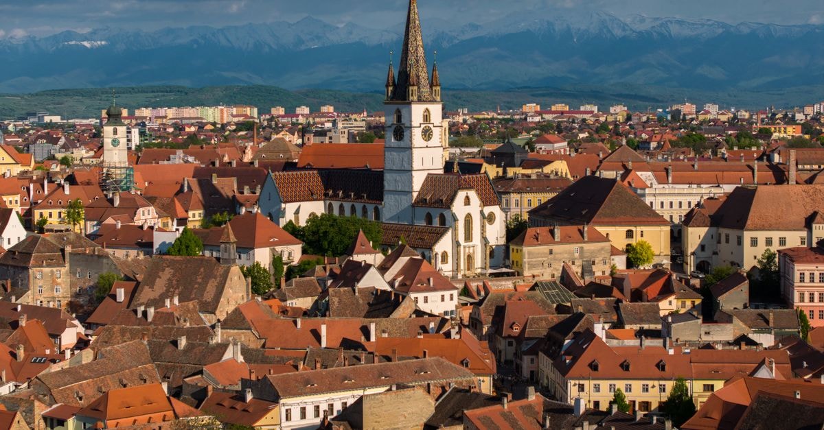 Aerial view of Sibiu, Romania showcasing historic architecture and mountainous backdrop.