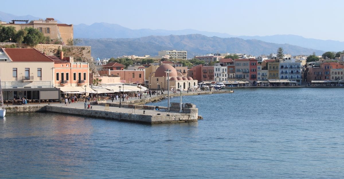 Samaria Hotel in Chania: A Poolside Stay Near the Old Town Scenic view of Chania harbor featuring traditional buildings and mountains in Greece.
