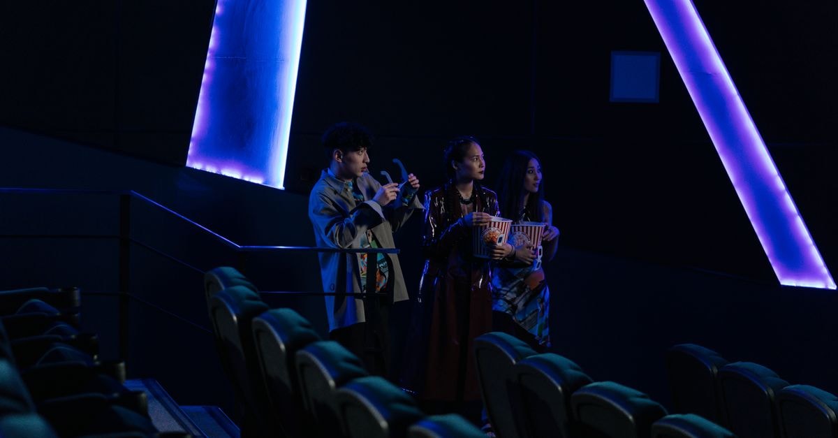 China's summer box office tops 7 billion yuan as Spider-Man: Brand New Day leads imported films Three friends standing in a dimly lit cinema holding popcorn, enjoying a movie night.