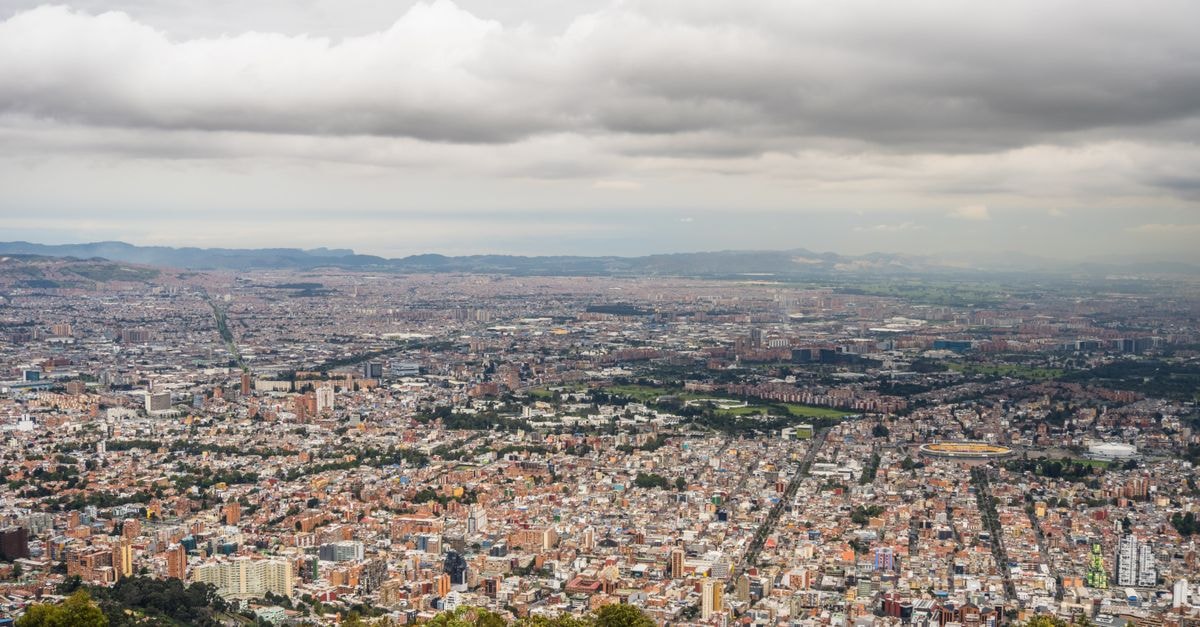 Hotel Nuevo Siboney, Bogotá: A Quiet Stay Near Los Mártires Expansive aerial view of Bogotá, Colombia, showcasing the dense urban cityscape under a cloudy sky.