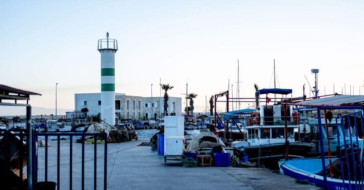 Dar Naim Travel Guide: Harbor Energy and Mauritanian Flavors Peaceful harbor scene in Foça, İzmir with boats and a lighthouse at dusk.