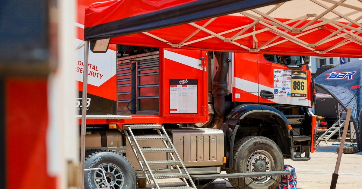 Sam Sunderland takes second at Red Bull Romaniacs on near-stock Triumph Tiger 900 Rally Pro A red rally truck preparing for an outdoor racing event, featuring tents and equipment.