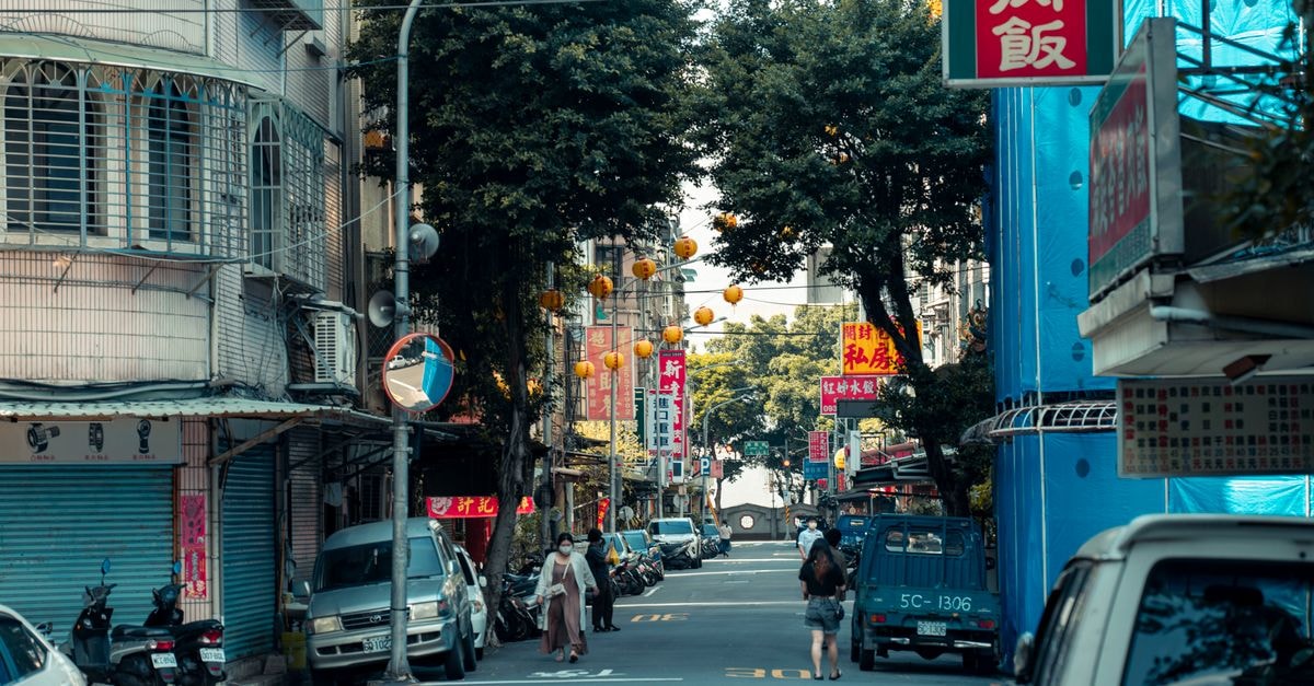 Chiayi Travel Guide: Planning Tips, Costs and Things to Do Street view in an urban area with parked vehicles and hanging lanterns, featuring vibrant Asian signage.