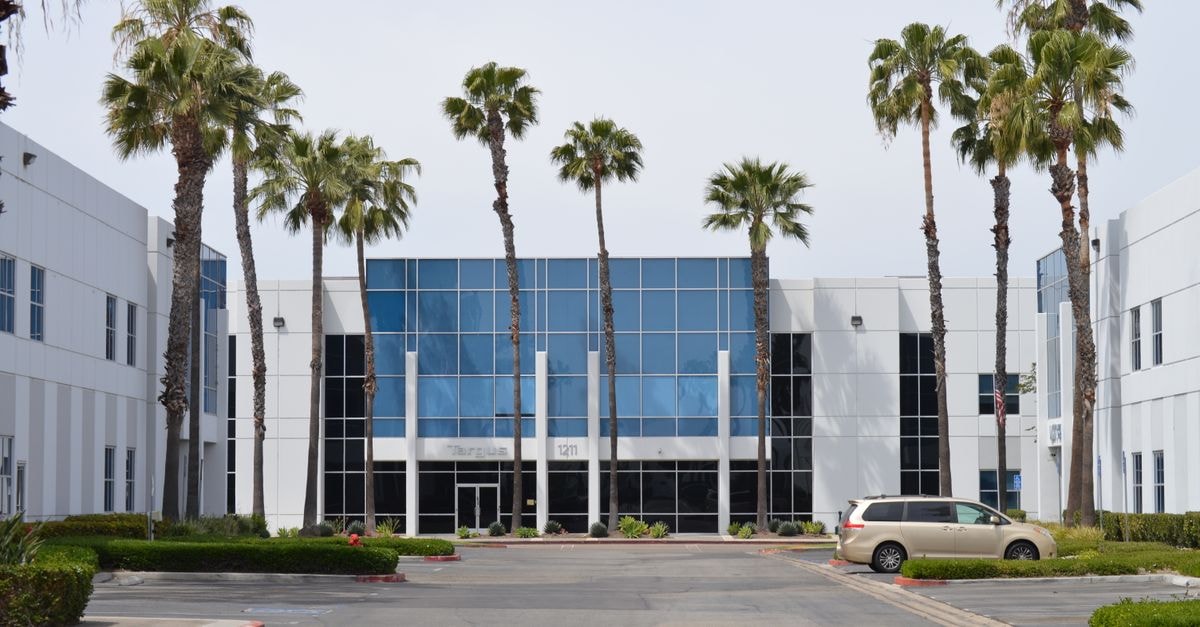 IDEXX Laboratories: A Quality Compounder Whose Price Demands a Long Wait Contemporary glass office building with palm trees and a parked car in daylight.